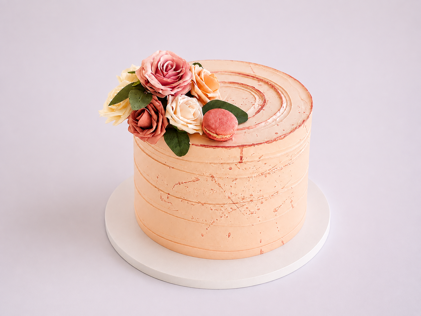 Peach custom cake decorated with handmade flowers and a pink macaron